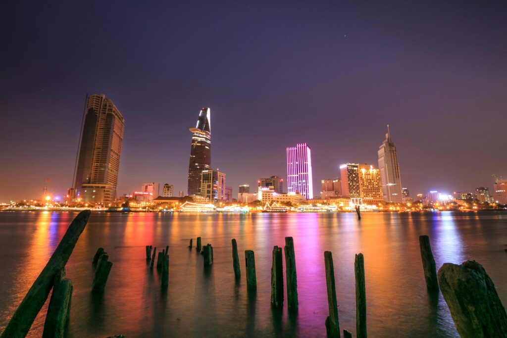 Illuminated skyline of Ho Chi Minh City reflecting on the water at night.